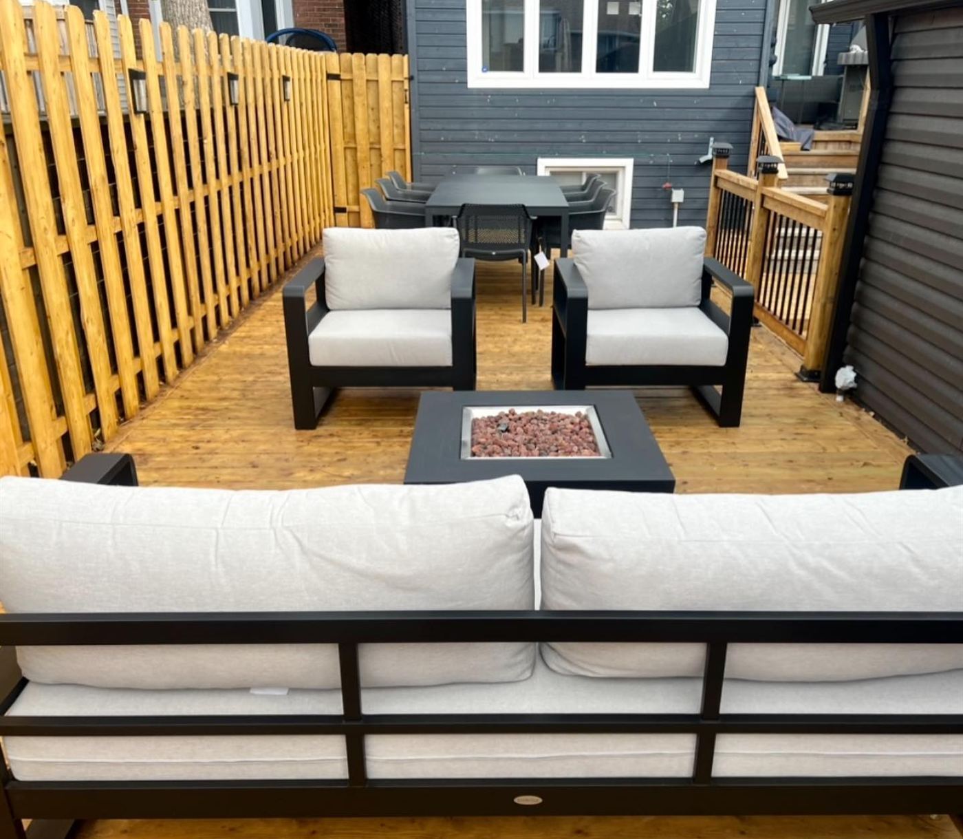 Deck seating around a fire table with dining set and new privacy fence